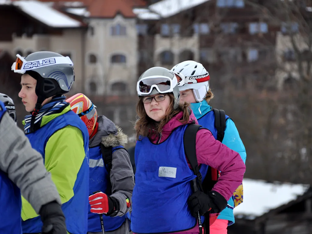 Jugendliche stehen in Skikleidung beisammen und unterhalten sich.